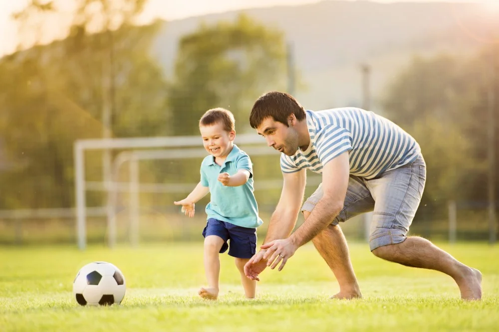 Far og søn der spiller fodbold